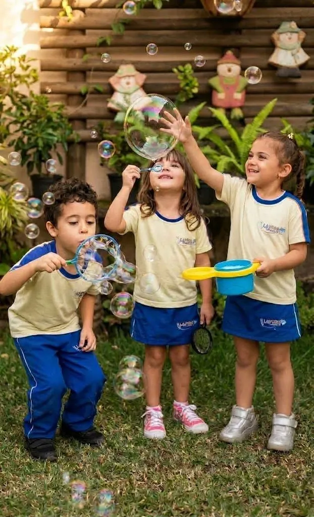 Crianças da Escola Lapidar brincando com bolhas de sabão no gramado, de uniforme