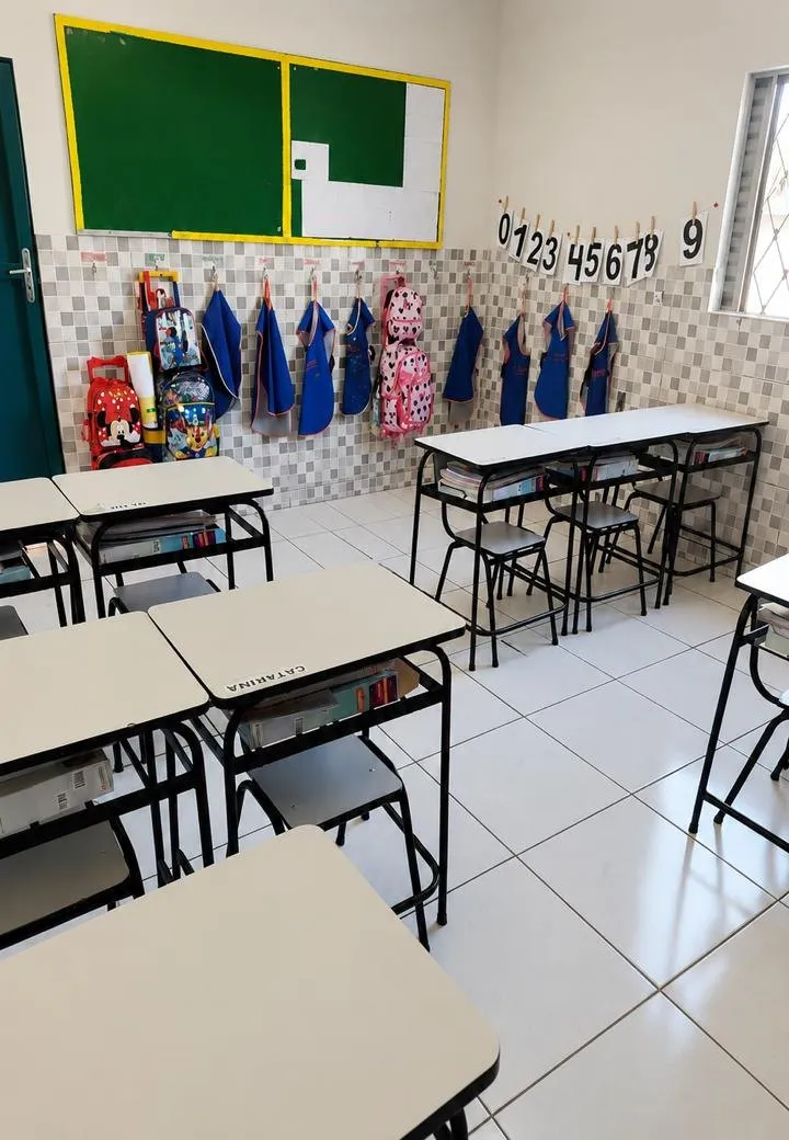 Sala de aula ampla e arejada da Escola Lapidar, com carteiras, aventais e material escolar